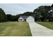 Charming one-story home with a well-manicured lawn and a long driveway leading to an attached garage at 188 Oakfield Trace Dr, Four Oaks, NC 27524