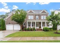 Beautiful two-story brick home with a welcoming front porch and manicured lawn at 213 Preatonwood Dr, Apex, NC 27539