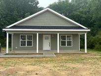 Charming single-story home with a covered front porch, white trim, and light green siding at 300 Saturn St, Dunn, NC 28334