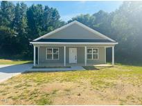 Charming single-story home featuring a covered porch and manicured lawn on a sunny day at 300 Saturn St, Dunn, NC 28334