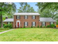 Charming brick home featuring a manicured lawn and vibrant red front door at 3027 Truitt Dr, Burlington, NC 27215