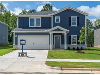 Charming two-story blue home featuring a well-manicured lawn, attached garage, and inviting front entrance at 3861 Rosebush Dr, Zebulon, NC 27597