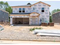 Unfinished two-story home with an attached two-car garage, surrounded by construction materials in a new community at 3861 Rosebush Dr, Zebulon, NC 27597