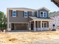 Two-story home featuring a gray exterior with a two-car garage and construction site at 3865 Rosebush Dr, Zebulon, NC 27597