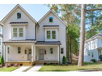 Charming two-story home featuring a welcoming porch, gray siding and black metal roof accents at 5053 Lundy Dr # 101, Raleigh, NC 27606