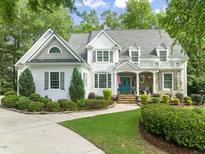 Charming two-story home features manicured landscaping, a blue front door, and a welcoming front porch at 5405 Bluet Ct, Holly Springs, NC 27540