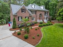 Beautiful brick home boasts manicured landscaping, healthy lawn, and a welcoming walkway to the front door at 5805 Laurel Rock Ln, Raleigh, NC 27613