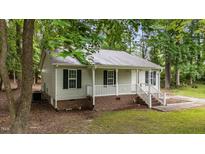Charming single-story home featuring light siding, black shutters, and a welcoming front porch with white railings at 627 Gaslight Trl, Wendell, NC 27591