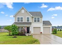 Charming two-story home with a manicured lawn, two-car garage, and welcoming curb appeal on a beautiful day at 66 Arlie Ln, Lillington, NC 27546
