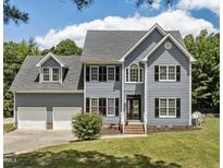 Charming two-story home boasts a manicured lawn, classic shutters, and an attached two car garage at 102 Ridge Ln, Youngsville, NC 27596