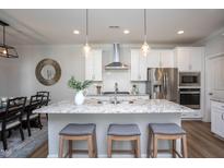 Bright kitchen features a granite island, stainless steel appliances, and white cabinets at 1048 Flagler St, Durham, NC 27713