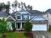 Beautiful two-story home featuring stone accents, a two-car garage, manicured lawn, and lush landscaping at 110 Elmsford St, Durham, NC 27707