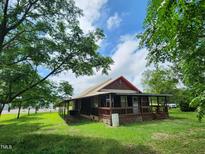Charming single-story home with a welcoming porch and lush green lawn under a blue sky at 111 Matthews Mill Pond Rd, Angier, NC 27501