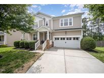 Charming two-story home with a manicured lawn, two-car garage, and covered front porch at 1211 Whispering Oak Ln, Durham, NC 27704
