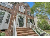 Inviting brick home featuring a classic front door with white columns and brick steps with white railings at 1309 Caribou Xing, Durham, NC 27713