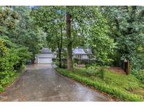 Traditional home with mature trees, attached garage, and a long driveway on a lush, green lot at 1311 Theodore Ln, Durham, NC 27703