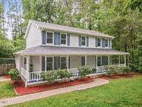 Charming two-story home with light gray siding, blue shutters, and inviting wrap-around porch with brick path at 14 Gloucester Ct, Durham, NC 27713