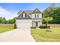 Charming two-story home featuring a manicured lawn, attached garage, and welcoming front entrance at 18 Dot Dr, Wendell, NC 27591
