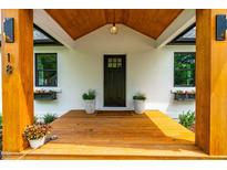 Inviting front entrance featuring a covered wood porch and black door flanked by flower-filled window boxes and planters at 18 W Academy St, Wendell, NC 27591