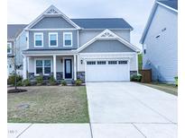 Charming two-story home featuring a two-car garage and inviting front porch seating area at 1950 Menet St, Apex, NC 27502