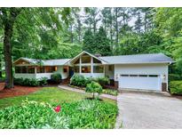 Charming single-story home with lush landscaping, bright white exterior, and attached two-car garage at 2004 Flagstone Pl, Raleigh, NC 27612