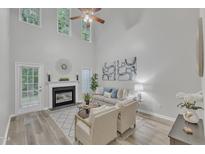 Bright living room featuring high ceilings, large windows, fireplace, and modern decor at 220 Misty Groves Cir, Morrisville, NC 27560