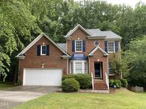 Charming brick home featuring blue shutters, a well-manicured lawn, and an attached two-car garage at 306 Fincastle Dr, Cary, NC 27513