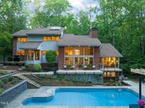 Inviting pool with stone surround and backyard deck, surrounded by lush green trees in a secluded location at 3910 Somerset Dr, Durham, NC 27707