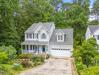 Charming two-story home featuring a front porch, attached garage, and mature trees at 4705 Royal Troon Dr, Raleigh, NC 27604