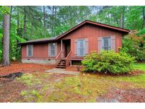 Charming single-story home featuring a wooden exterior, shuttered windows, and a landscaped front yard at 506 E E St, Butner, NC 27509