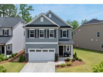 Charming two-story home featuring a gray exterior, manicured lawn, and a welcoming two-car garage at 6036 Balance Ct, Raleigh, NC 27616