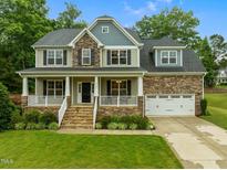 Charming two-story home with a welcoming front porch, manicured lawn, and attached two-car garage in a lovely community at 6949 Rex Rd, Holly Springs, NC 27540