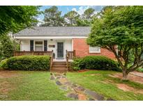 Charming home featuring a brick accent, a wood porch, and a quaint stone walkway at 729 Mial St, Raleigh, NC 27608