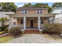 Inviting home featuring a charming front porch with white pillars, a red front door, and a well-maintained landscaped yard at 803 W Club Blvd, Durham, NC 27701
