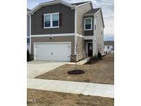 Inviting two-story home showcasing a well-maintained lawn, attached garage and neutral color palette at 909 Clearhaven Ln # 909, Fuquay Varina, NC 27526