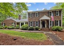 Charming brick home with black shutters, an American flag, and beautiful landscaping at 102 Mel Oak Dr, Chapel Hill, NC 27516