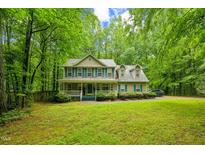 Charming two-story home featuring a welcoming front porch and lush landscaping surrounded by mature trees at 115 Redbay Ln, Clayton, NC 27527