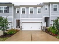 Charming townhome showcasing gray siding, a two-car garage, and manicured landscaping at 1213 Grenshaw Dr, Morrisville, NC 27560