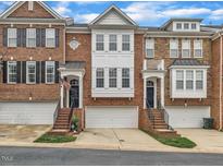 Charming brick townhomes featuring attached garages, lovely architectural details, and well-manicured landscaping at 2744 Laurelcherry St, Raleigh, NC 27612
