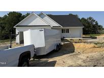 New construction with white siding, black roof, and trailer in the driveway at 2744 Rains Mill Rd, Princeton, NC 27569