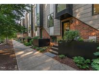 Modern townhome exterior featuring a mix of brick and metal siding, plus attractive planters at 414 Chavis Way, Raleigh, NC 27601