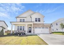 Beautiful two-story home with a brick and white siding, a two-car garage, and a well-manicured lawn at 604 Salmonberry Dr, Holly Springs, NC 27540