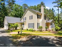 Traditional two-story home featuring a manicured lawn, brick walkway, mature trees, and a classic design at 676 Whitehurst, Pittsboro, NC 27312