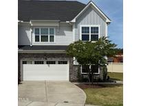 Charming two-story home featuring a gray exterior, stone accents, and an attached two-car garage, set against a blue sky backdrop at 1021 Benay Rd, Morrisville, NC 27560