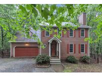Charming brown two-story home featuring red shutters, a chimney, and an attached two-car garage at 105 Trailwood Ct, Chapel Hill, NC 27516