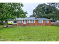 Charming brick home with a well-manicured lawn, lush trees and inviting front porch at 2016 Tryon Rd, Raleigh, NC 27603