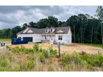 New construction home featuring Tyvek wrap, dormers, attached garage, and partially cleared lot ready for finishing touches at 204 Seahawk Way, Zebulon, NC 27597