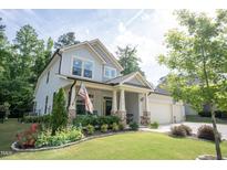 Charming two-story home with an American flag, landscaped yard, and inviting front porch at 212 Hardwick St, Clayton, NC 27527