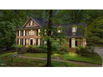Two-story brick home with a welcoming front porch, black shutters, and professional landscaping at 220 Dalton Dr, Raleigh, NC 27615