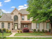 Stately brick home with beautiful landscaping, a welcoming entrance, and a large arched window at 2207 Cameron Pond Dr, Cary, NC 27519
